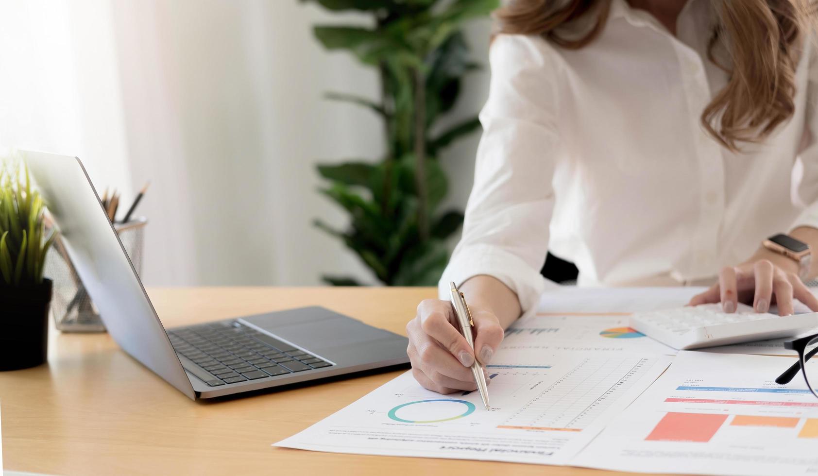 Businesswoman hand holding pen and pointing at financial paperwork with financial network diagram. photo