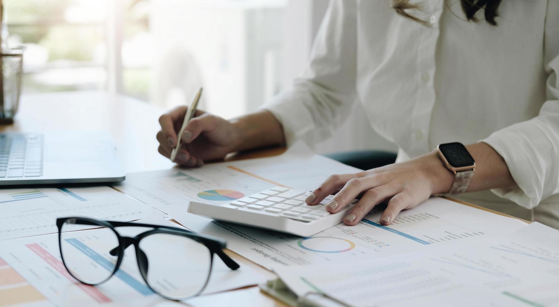 empresa de auditoría, la secretaria del inspector financiero de las mujeres de negocios informa sobre el cálculo, control del saldo. El servicio de impuestos internos inspecciona el documento de cheques con una computadora portátil y una calculadora. foto