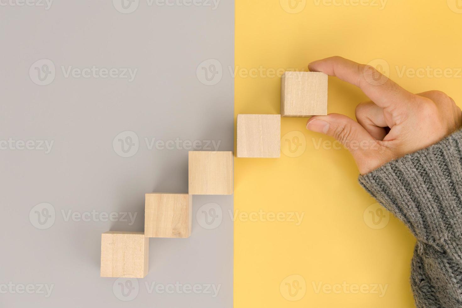 Mujer mano arreglando el bloque de madera vacío y copie el espacio sobre fondo gris y amarillo foto