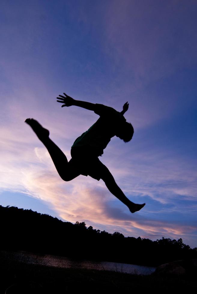 Silhouette happy jumping against beautiful in sunset. Freedom, enjoyment concept photo