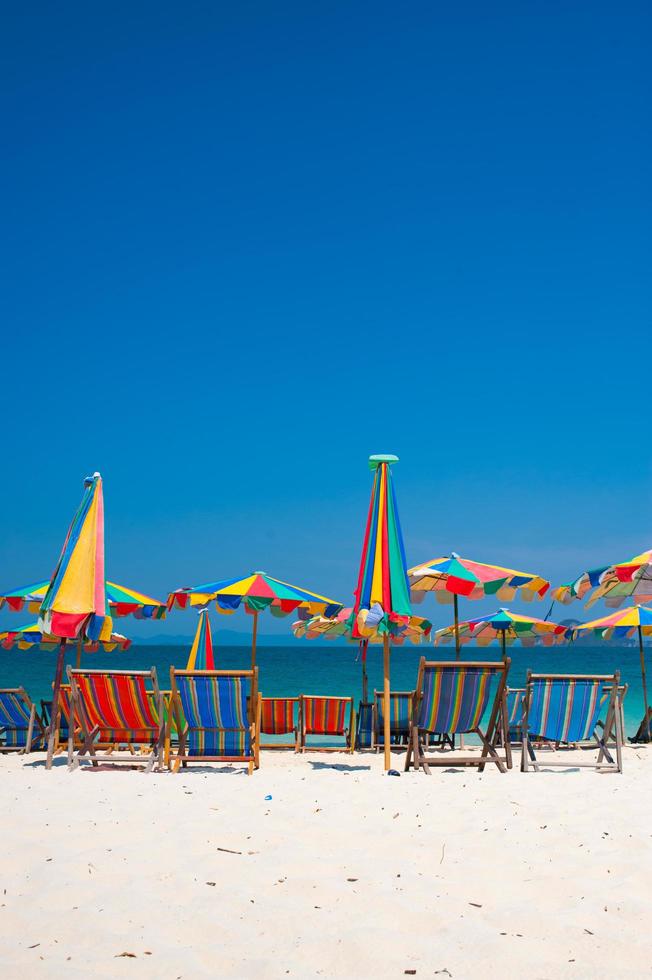 Silla de playa bajo la sombrilla de colorido en la playa de Phuket, Tailandia foto