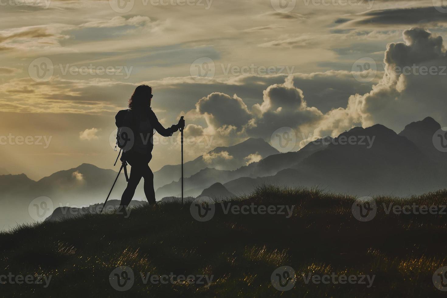 Walk in solitude on the Alps. A woman on with the background of abstract mountains in the clouds photo