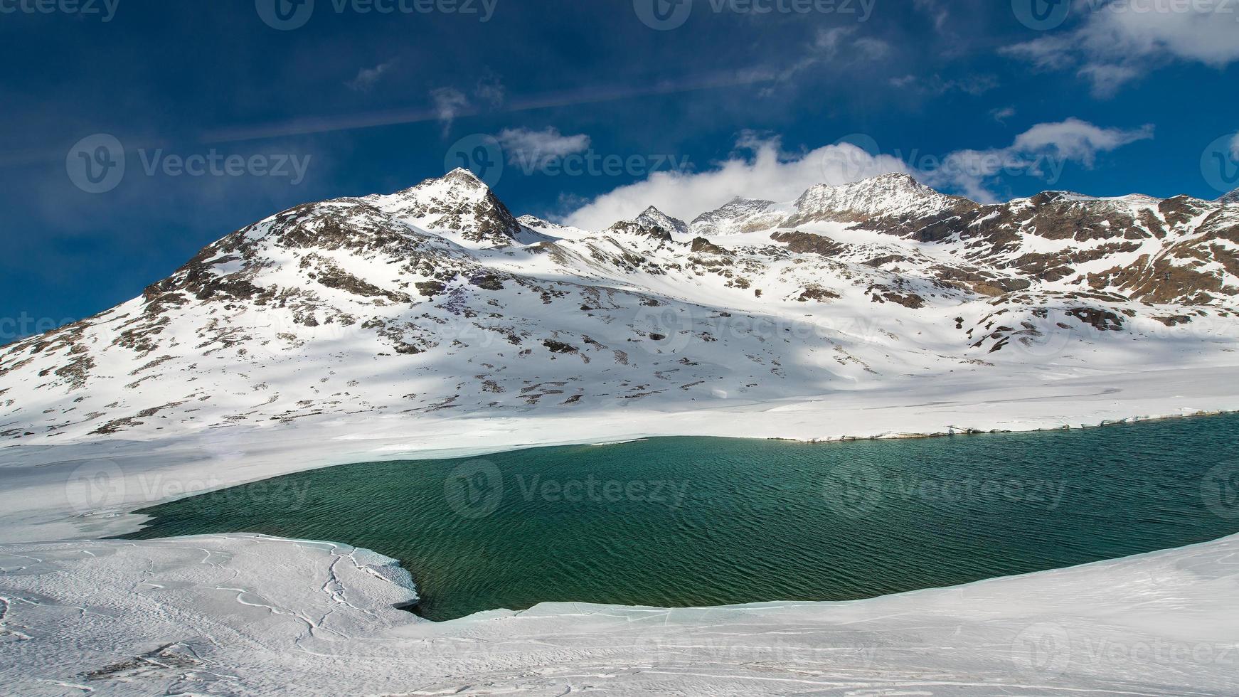 Deshielo en un paisaje de alta montaña con un lago. foto