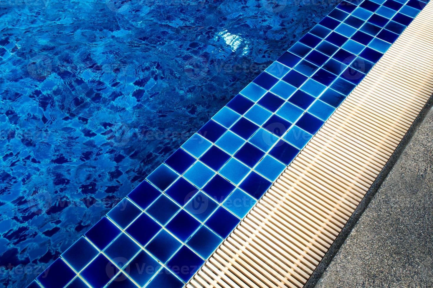 Pisos de baldosas de cerámica azul y canaletas de drenaje junto a la piscina foto