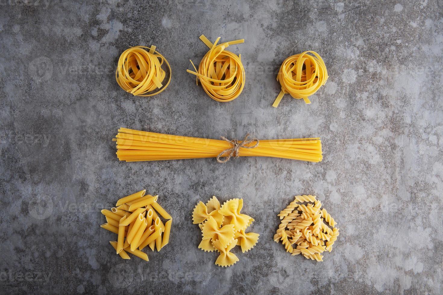 Five types of different pasta lie on a gray table photo