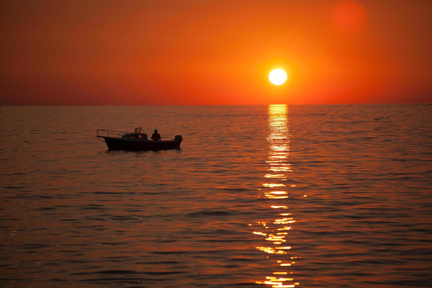 pescador en un barco durante la puesta de sol foto