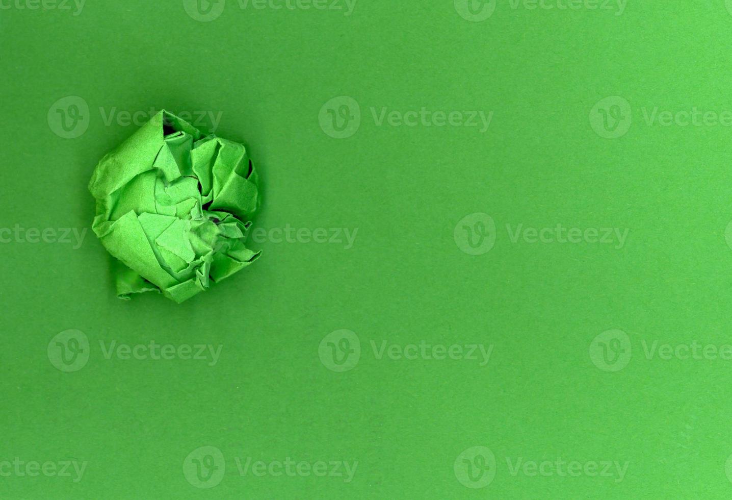 Green paper ball over green cardboard background photo