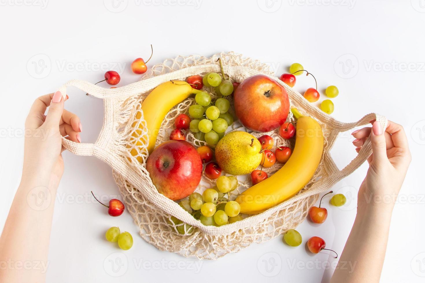 Las manos de las mujeres sostienen una bolsa de malla ecológica con frutas. comida vegana orgánica. concepto de estilo de vida sostenible y cero residuos. foto