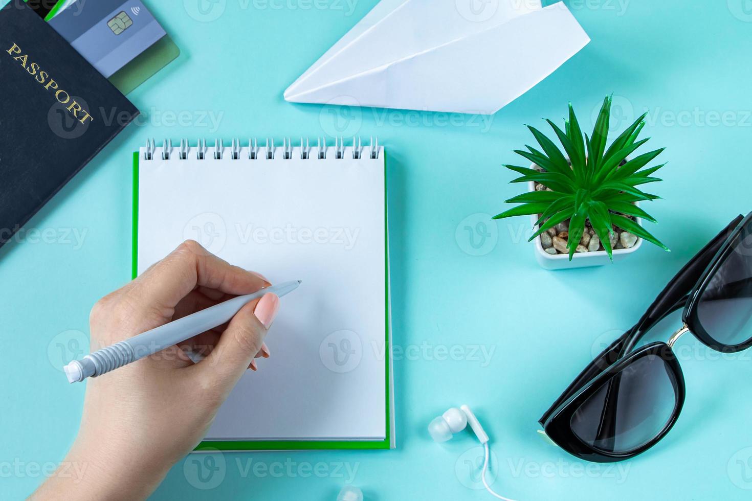 A woman is planning a summer vacation. Travel accessories on a blue background. Passport, sunglasses and notepad. photo