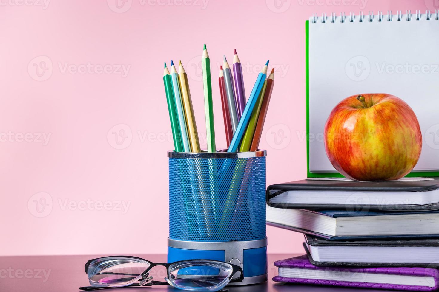 Back to school concept. School supplies, books and apple on pink background. Place for text. photo