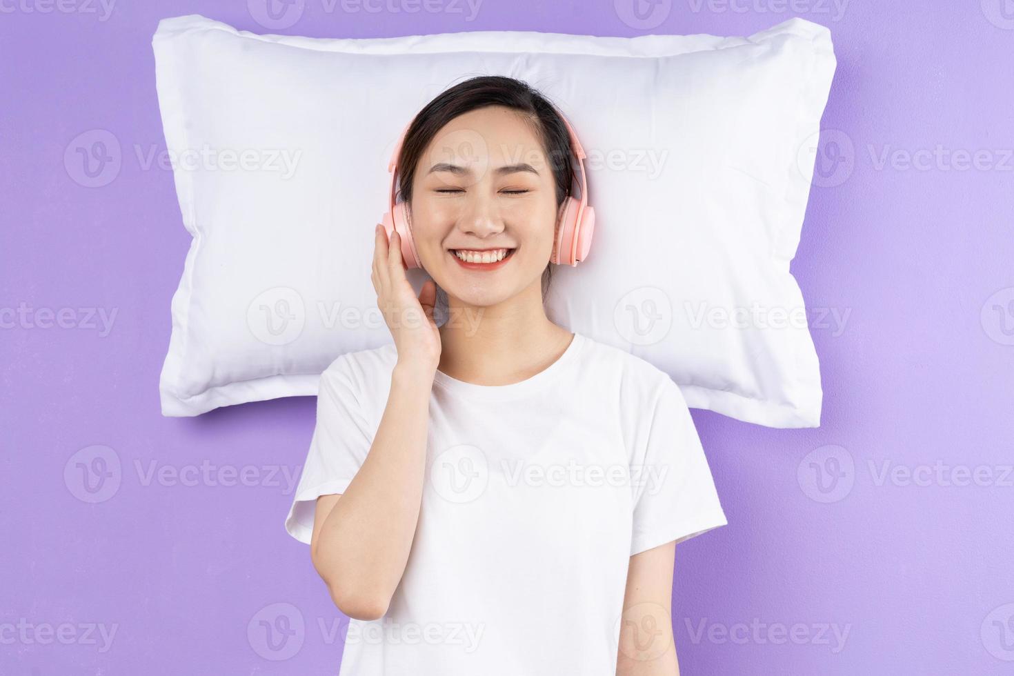 Asian woman holding upper pillow, isolated on purple background photo