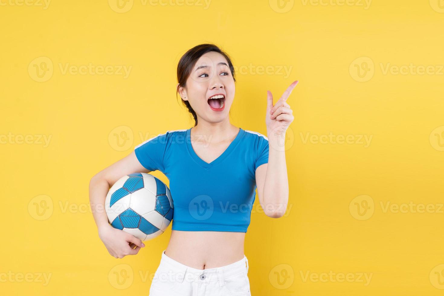 portrait of young dynamic girl holding ball in hand isolated on yellow background photo