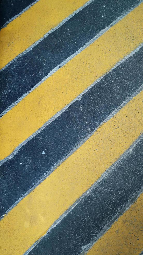 Fondo de patten de advertencia de precaución negro y amarillo en el suelo. foto