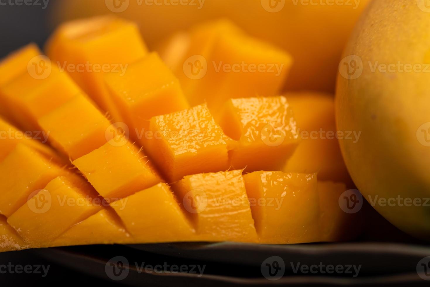 Cerca de trozos de mango cortado contra un fondo oscuro foto