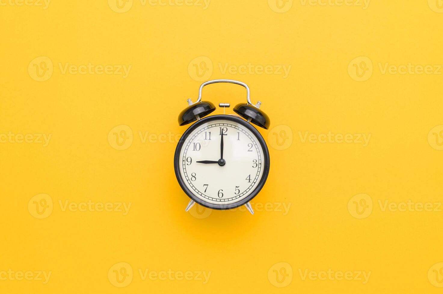 An alarm clock on a yellow background photo