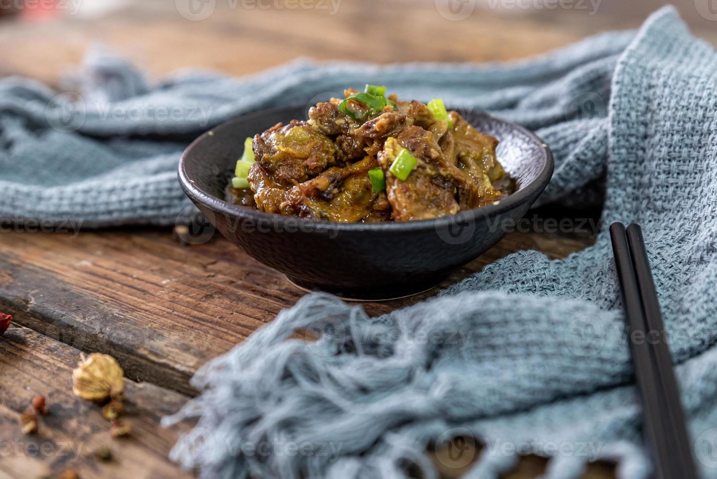 The food made of beef is in the bowl on the cloth of the wooden table photo