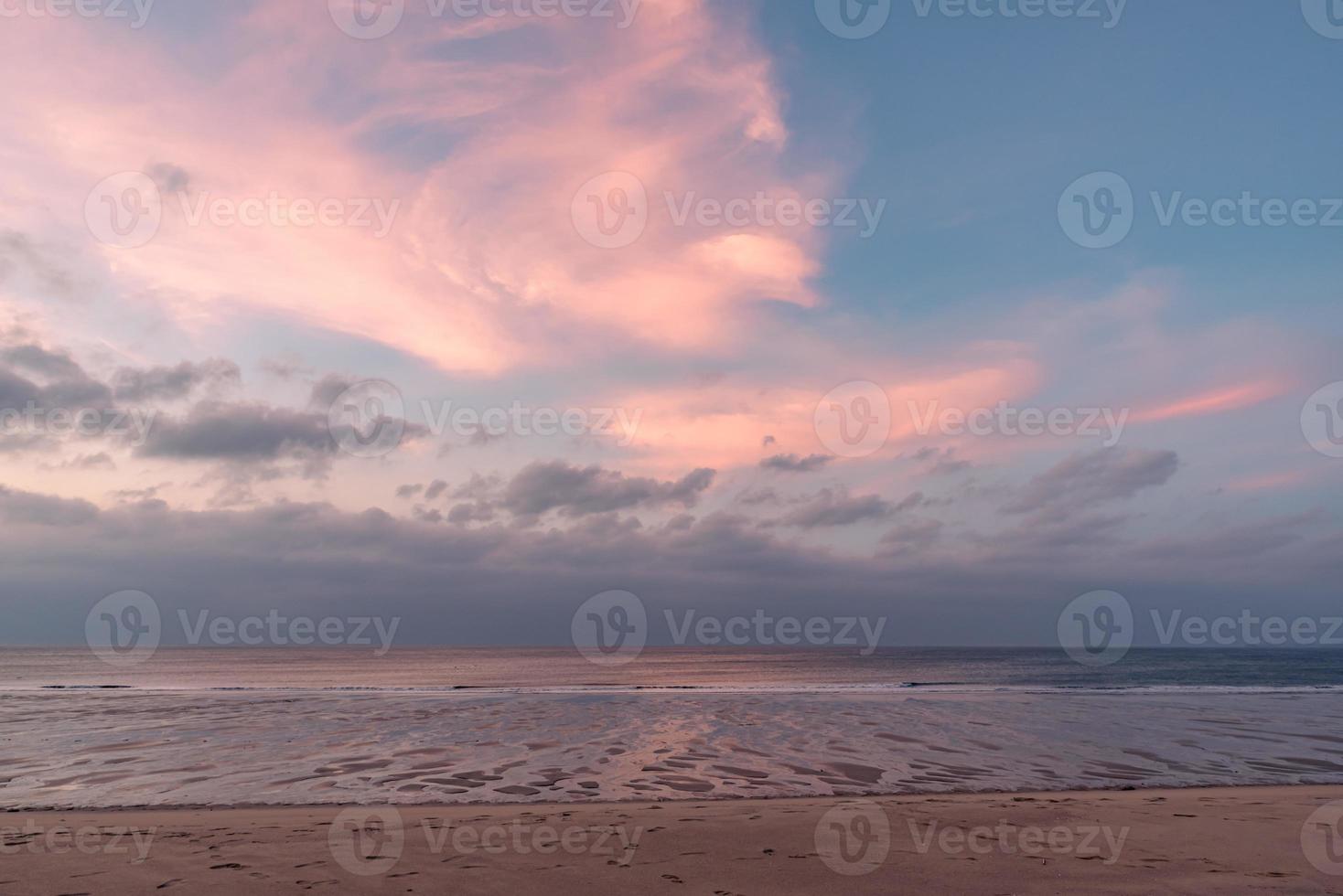 In the early morning by the sea, the sky and the beach are slightly red photo