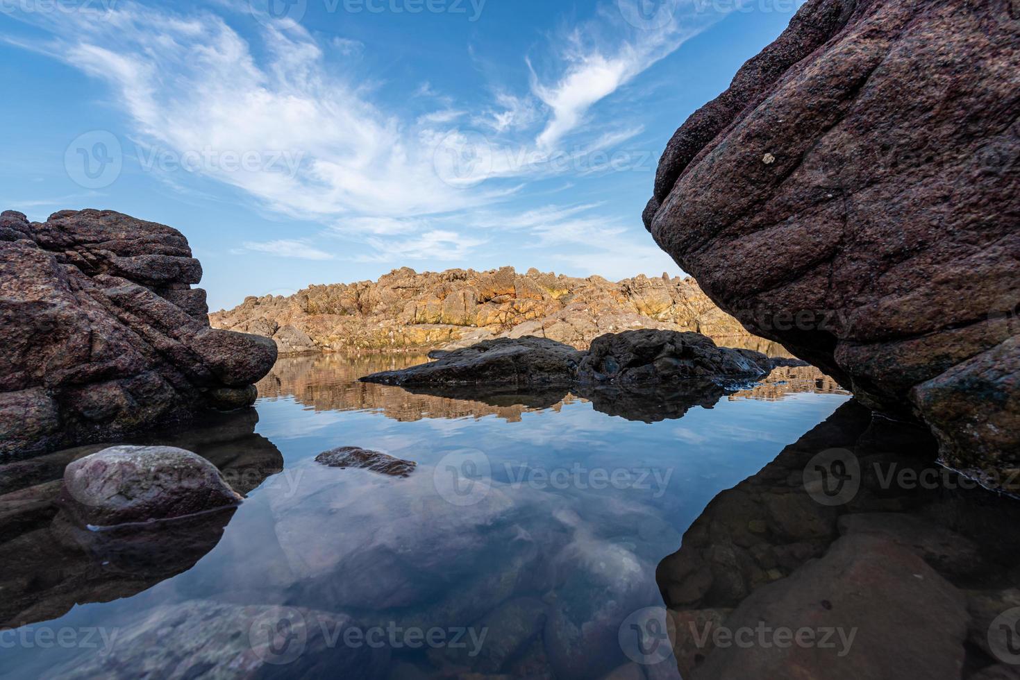 el agua del mar entre los arrecifes costeros refleja los arrecifes amarillos y el cielo azul foto