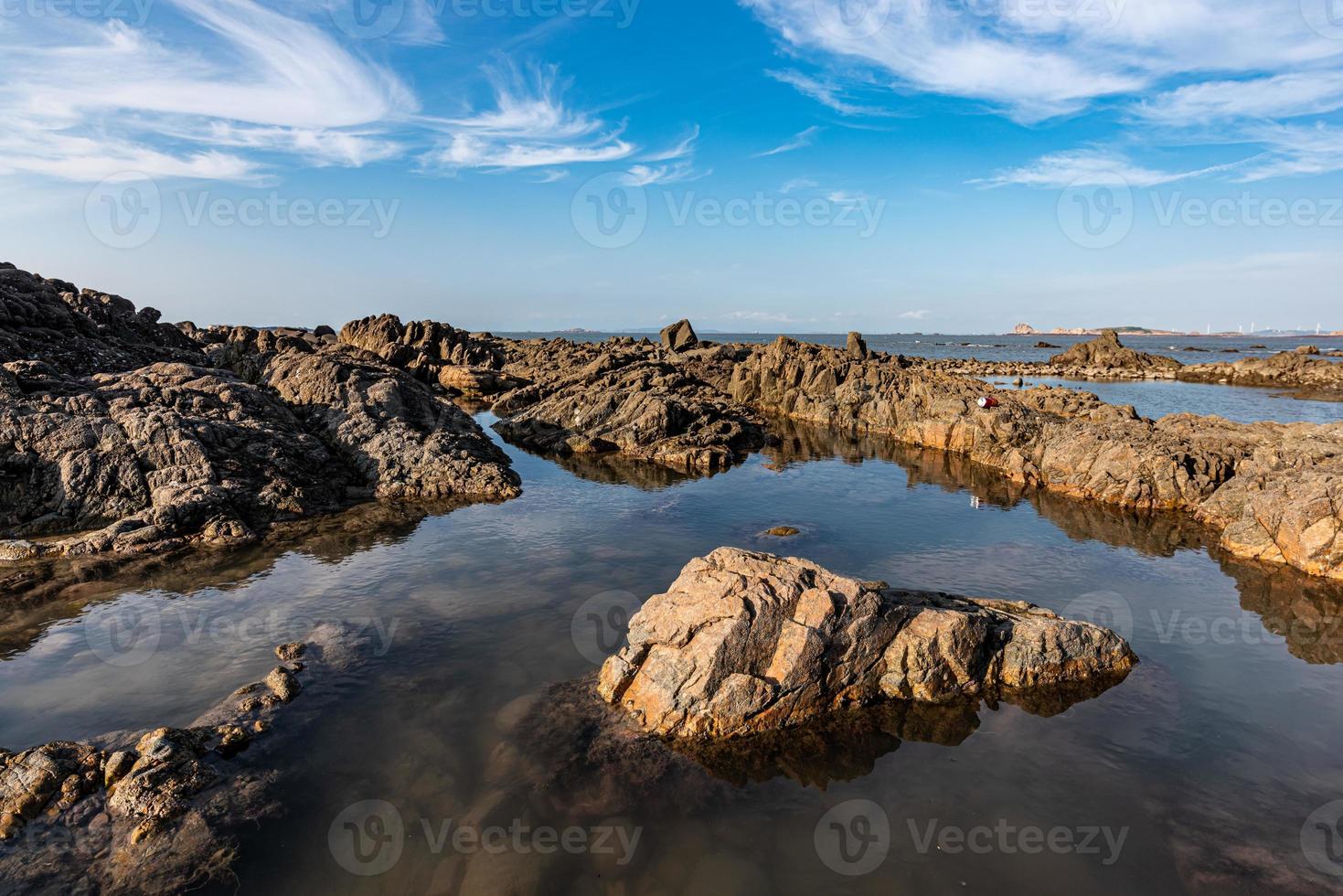 el agua del mar entre los arrecifes costeros refleja los arrecifes amarillos y el cielo azul foto