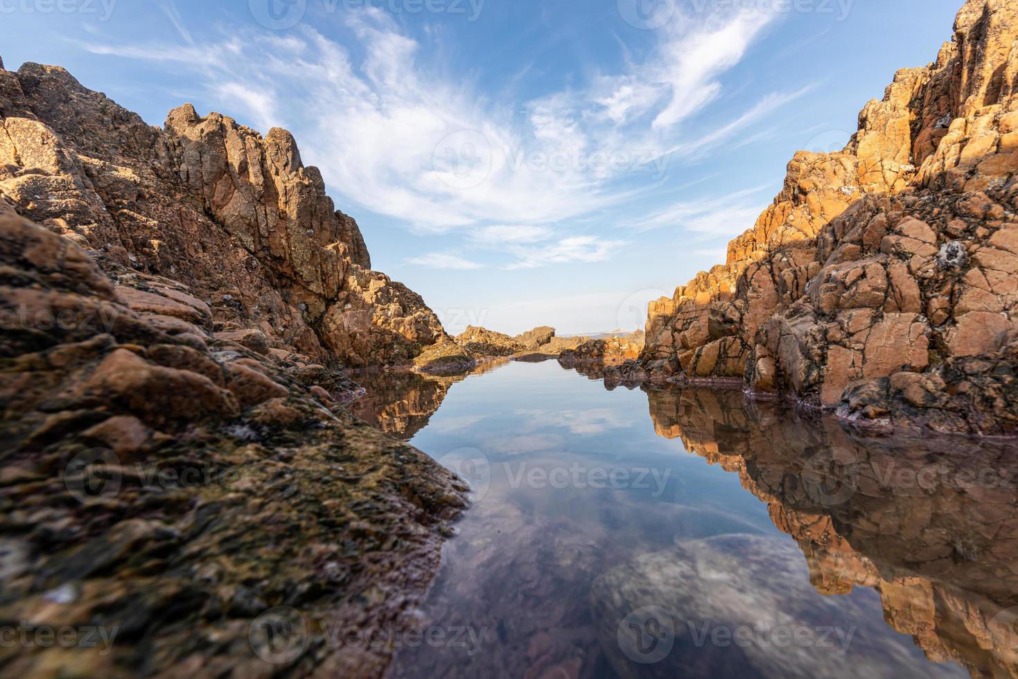 The sea water between the seaside reefs reflects the Yellow reefs and the blue sky photo