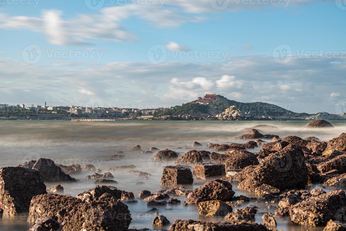 por la mañana, el sol brilla sobre las rocas y las olas en la playa foto