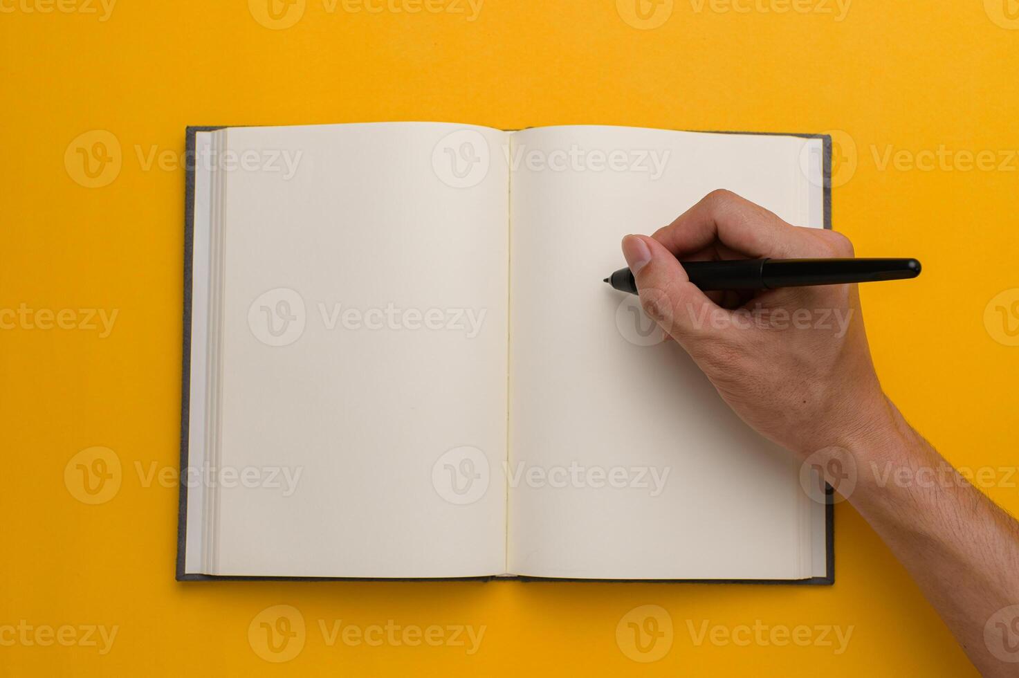 Hand writing in blank notebook on yellow background photo