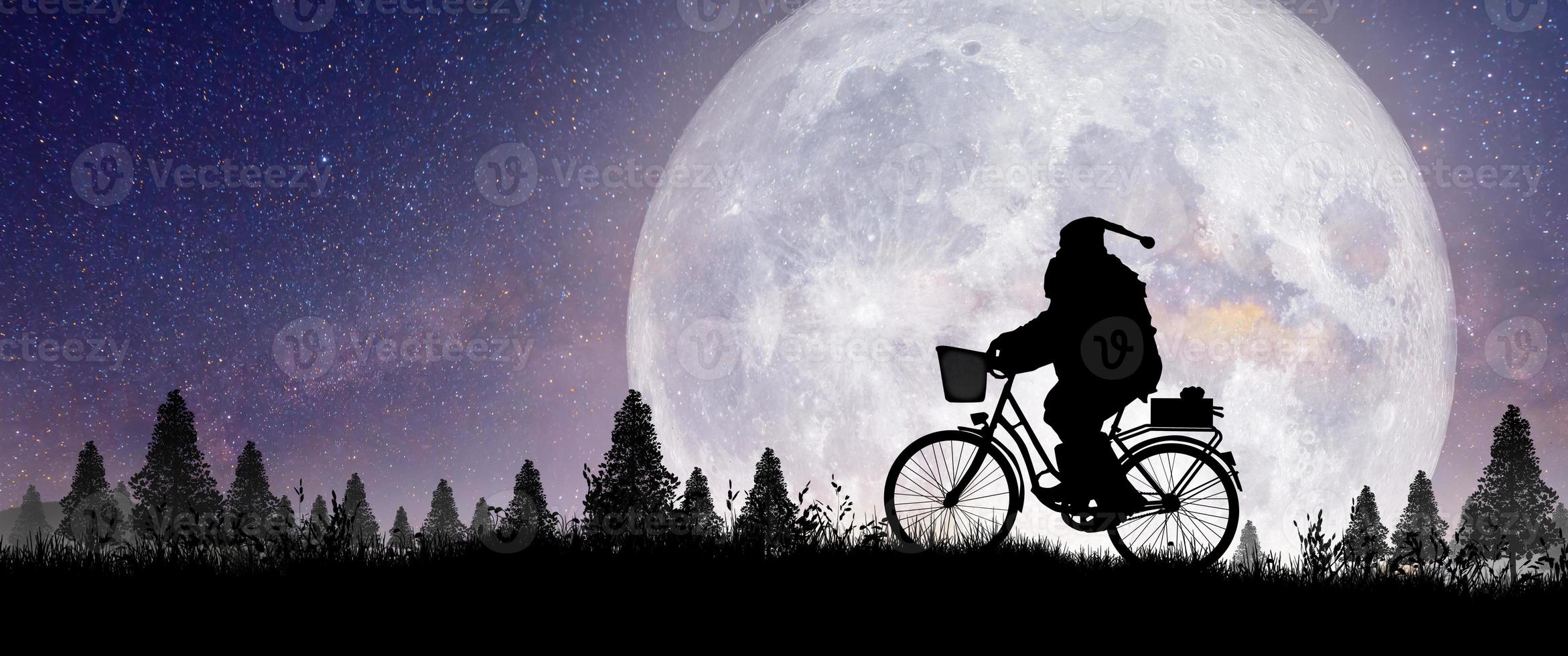 silueta de santa claus montando en su bicicleta sobre la luna llena. foto