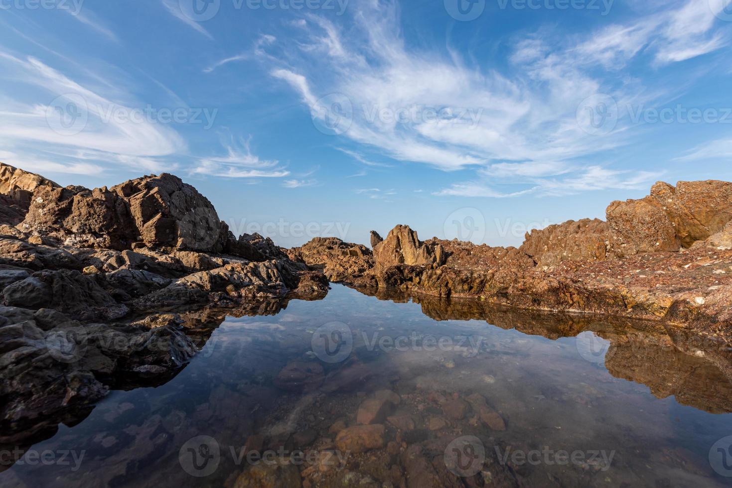 el agua del mar entre los arrecifes costeros refleja los arrecifes amarillos y el cielo azul foto