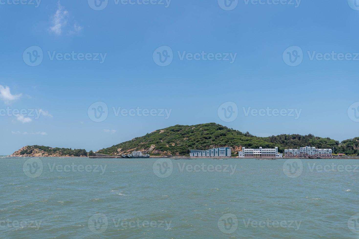 el mar y la costa bajo un cielo azul y nubes blancas foto