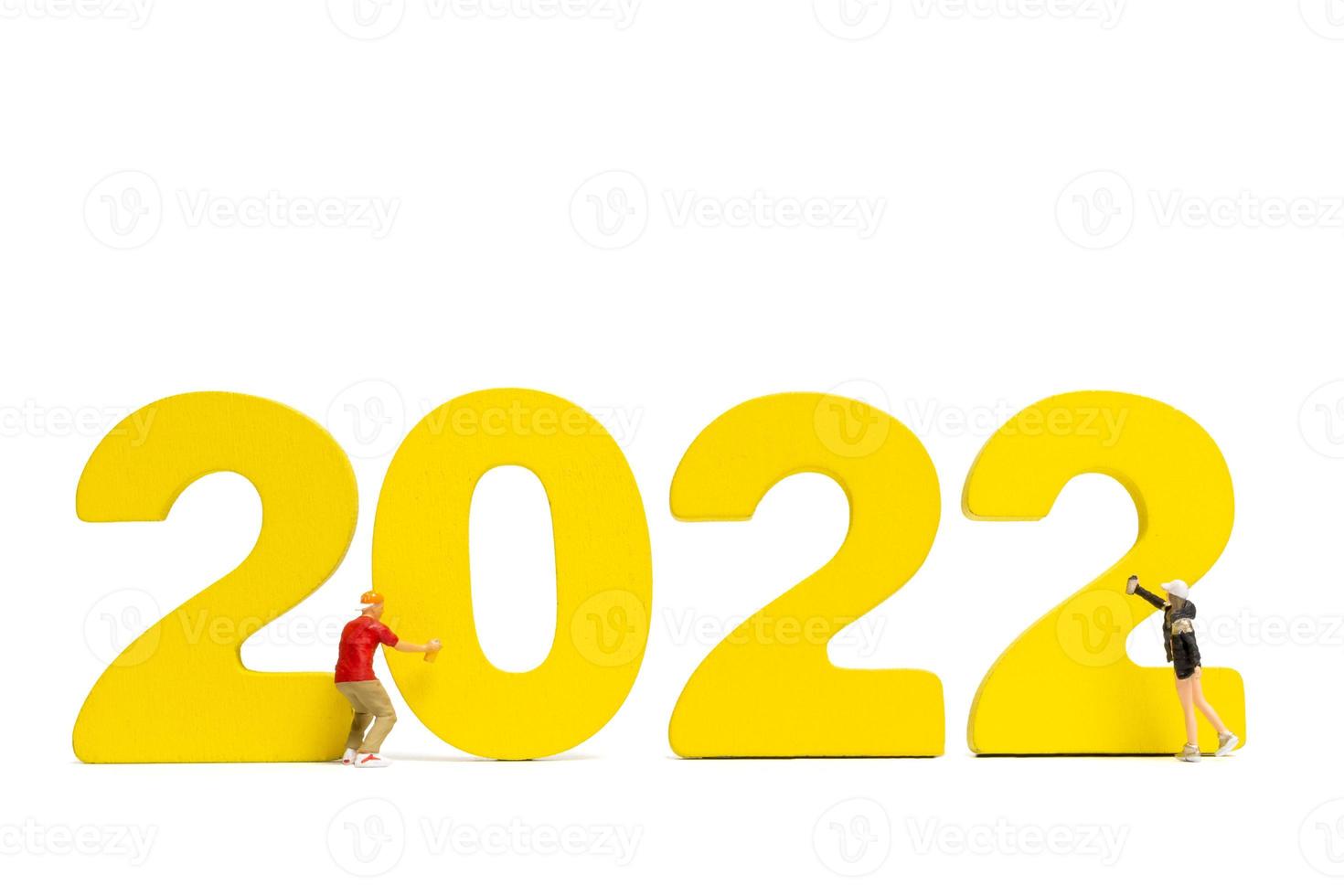 La gente en miniatura adolescente rociar pintura número 2022 sobre fondo blanco. foto