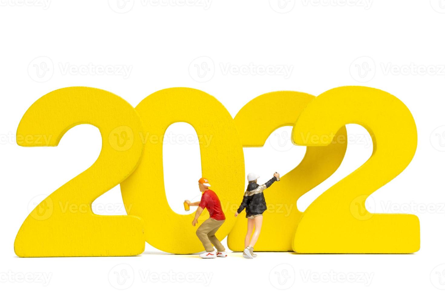 Miniature people Teenager spraying paint Number 2022 on white background photo