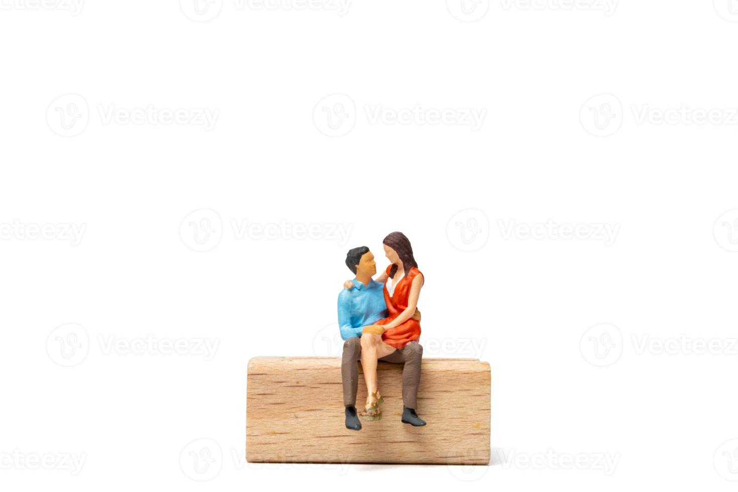 Pareja de personas en miniatura sentada en una silla de madera y espacio para tex foto