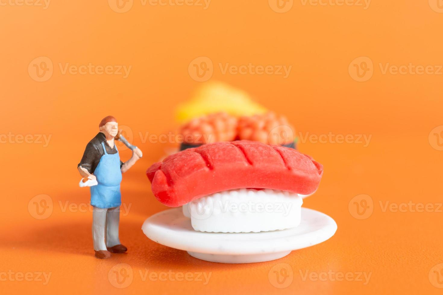 Tiny Chef making Sushi set on orange background photo