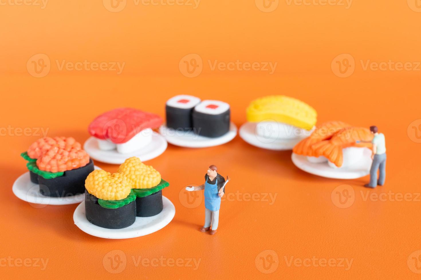 Tiny Chef making Sushi set on orange background photo