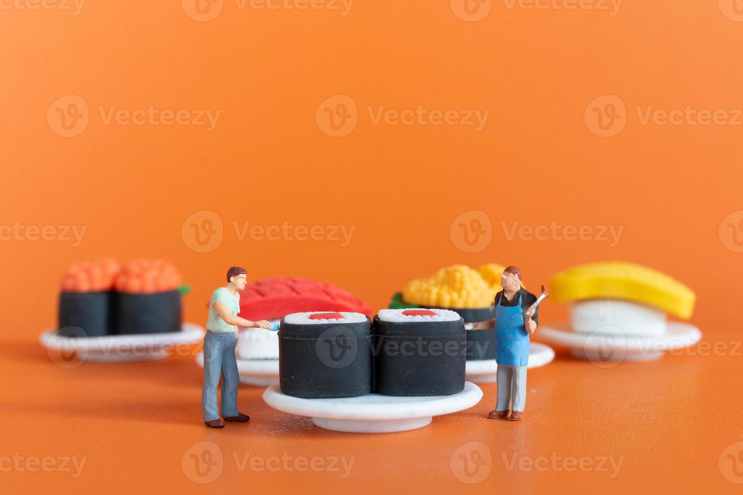 Tiny Chef making Sushi set on orange background photo