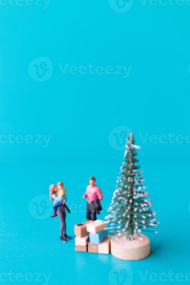 Miniature people, Happy Family standing next to a Christmas tree photo