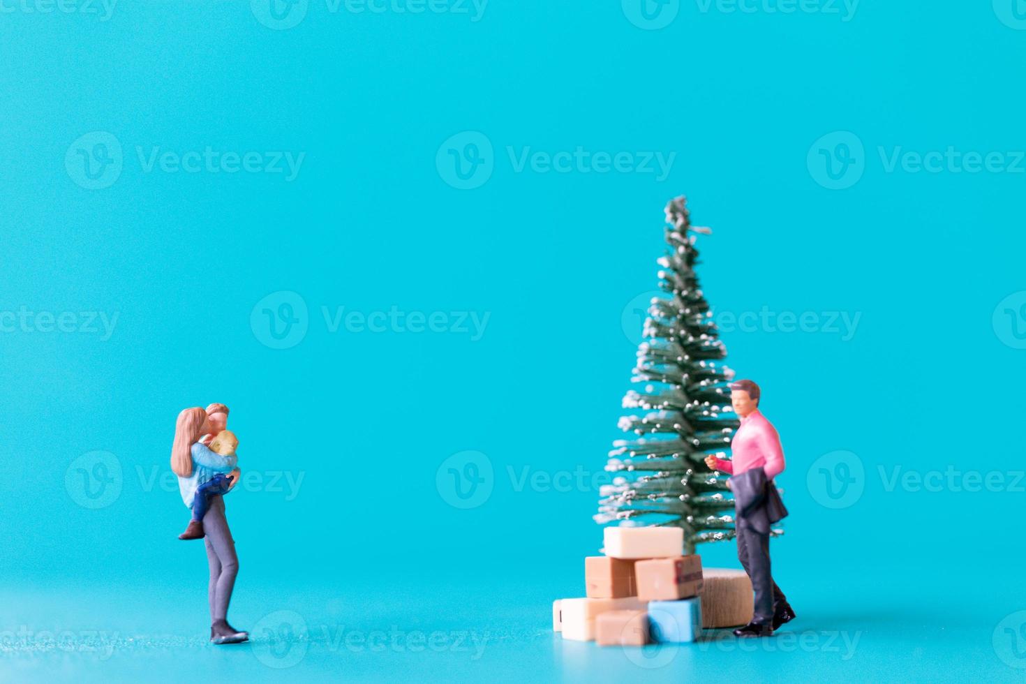 gente en miniatura, familia feliz de pie junto a un árbol de navidad foto