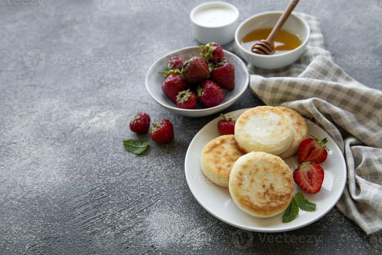 tortitas de requesón, buñuelos de ricotta en plato de cerámica con fresa fresca. foto