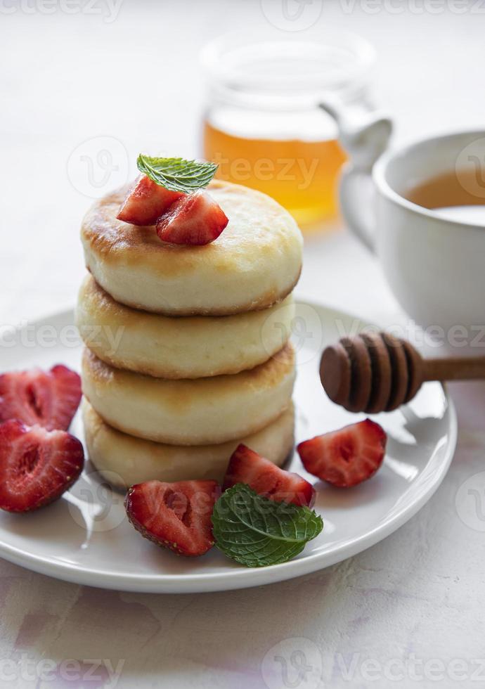 Cottage cheese pancakes, ricotta fritters on ceramic plate with  fresh strawberry. photo