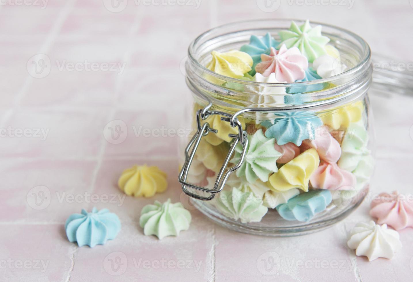 Small colorful meringues in the glass jar photo