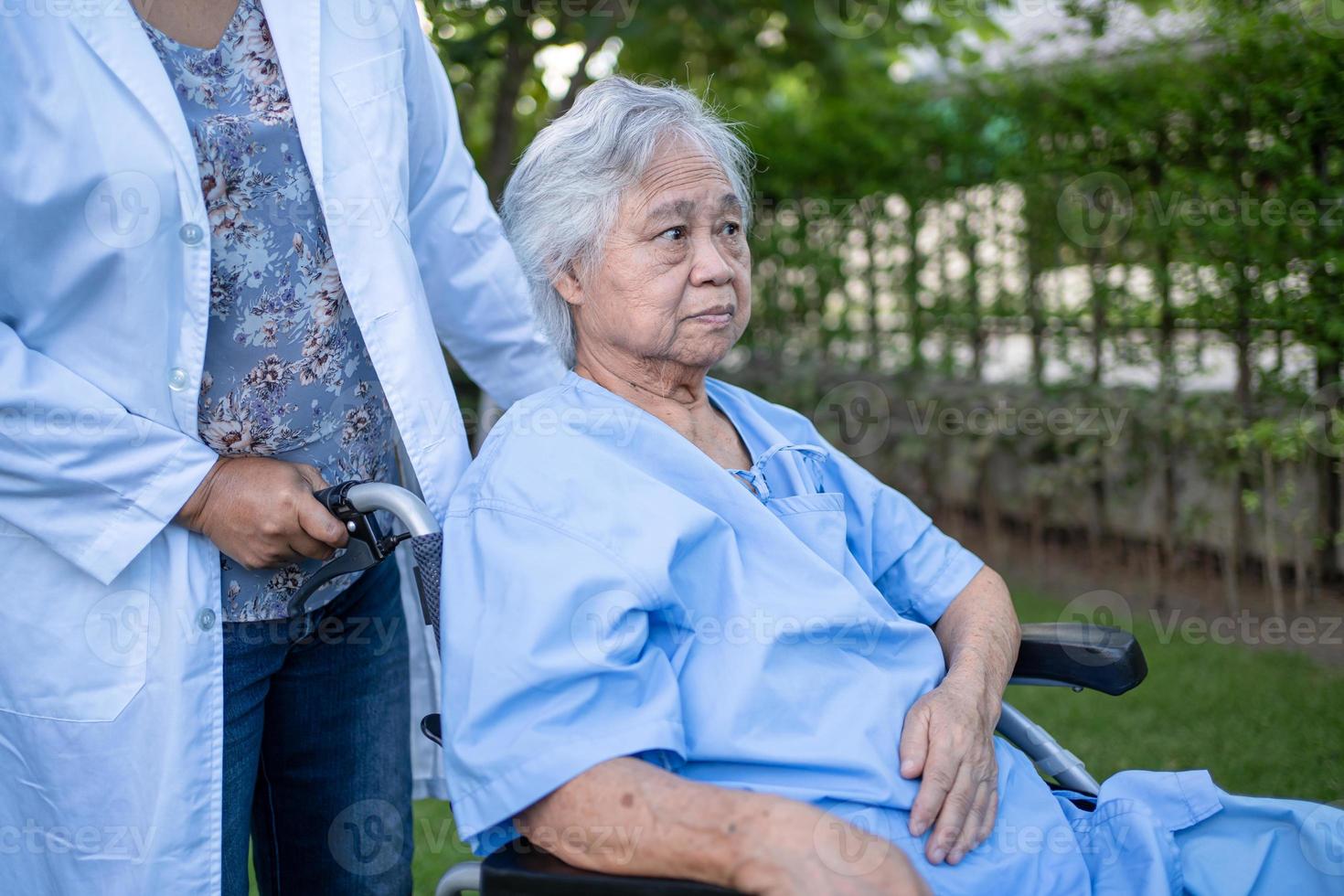 Doctor help and care Asian senior or elderly old lady woman patient sitting on wheelchair at park in nursing hospital ward, healthy strong medical concept. photo