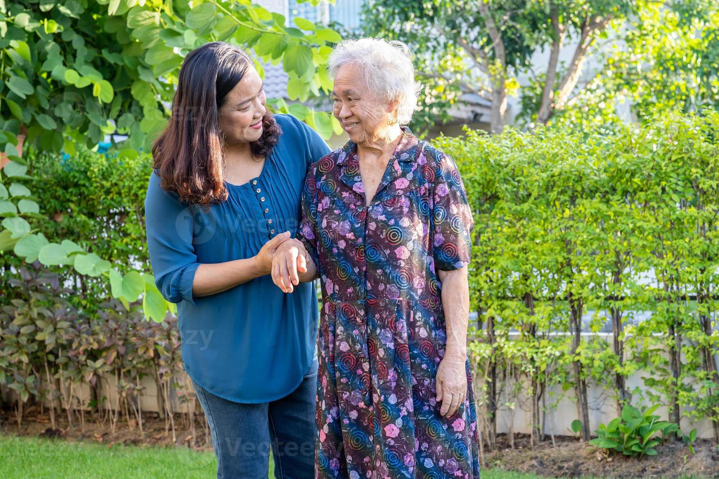 Asian elderly woman with caregiver walking with happy in nature park. photo