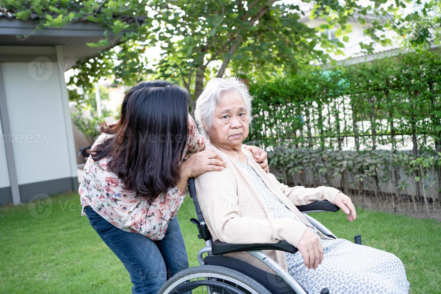 Ayude a la anciana asiática mayor o anciana en silla de ruedas eléctrica y use una mascarilla para proteger la infección de seguridad Covid 19 coronavirus en el parque foto