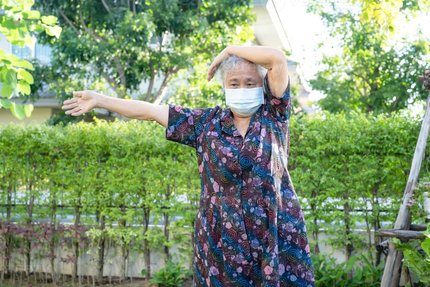 Mujer mayor asiática con máscara protege el ejercicio de coronavirus con feliz en el parque, concepto médico fuerte y saludable foto
