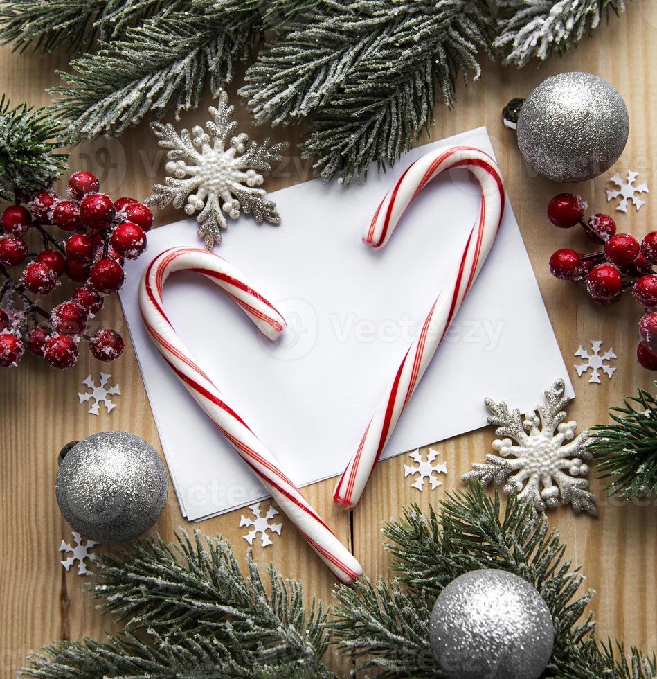 Fondo de madera navideña, tarjeta con decoración navideña, bastones de caramelo navideño, bolas navideñas y rama de abeto, foto