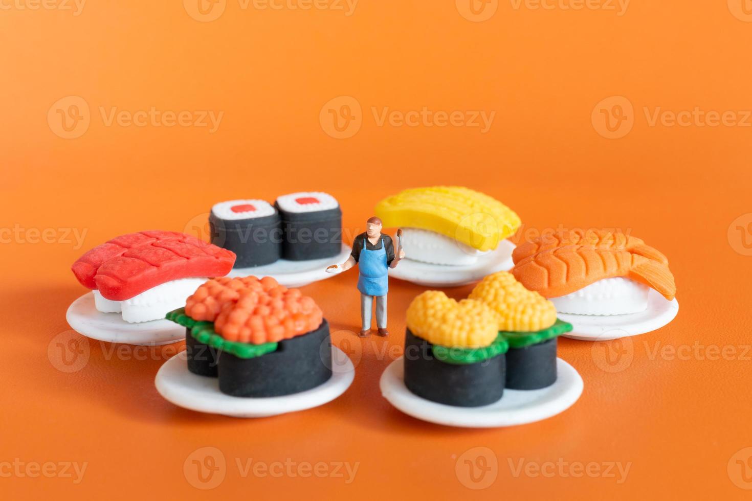 Tiny Chef making Sushi set on orange background photo