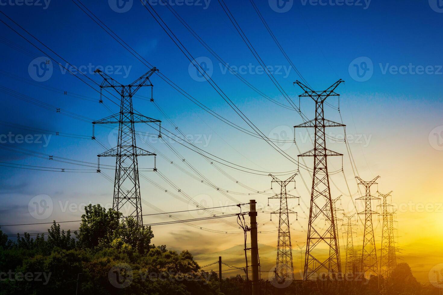 Sun setting behind the silhouette of electricity pylons photo