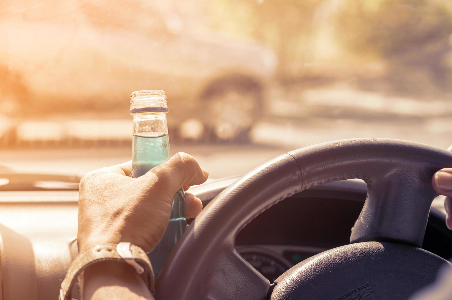 Don't drink and drive concept, Drunk and driving a car with a bottle of alcohol photo