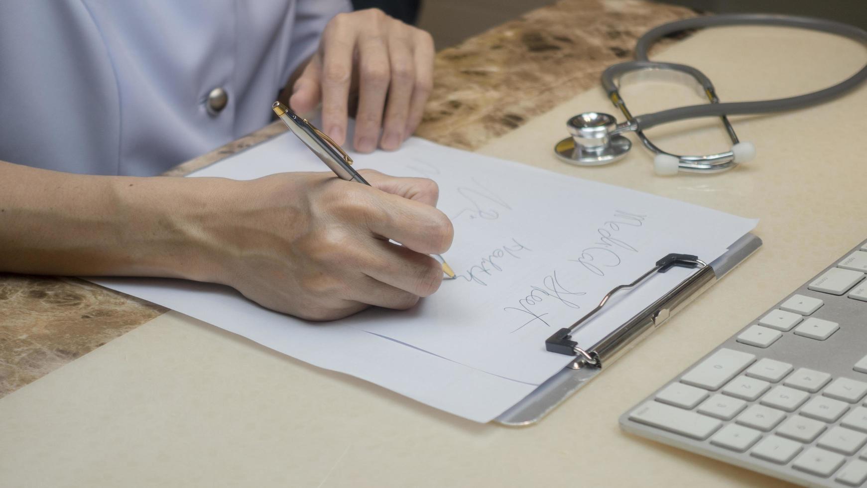 Femal doctor writing down a prescription on a sheet of paper in hospital. photo