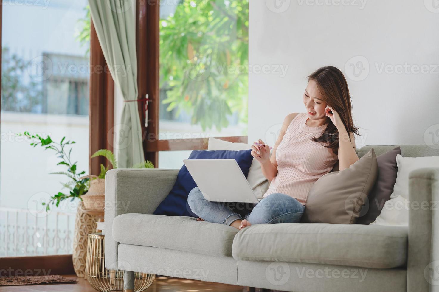 Mujer asiática sonriendo mientras usa el portátil en casa foto